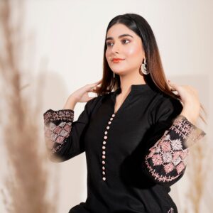 Fashionable woman in an embroidered dress posing elegantly indoors.